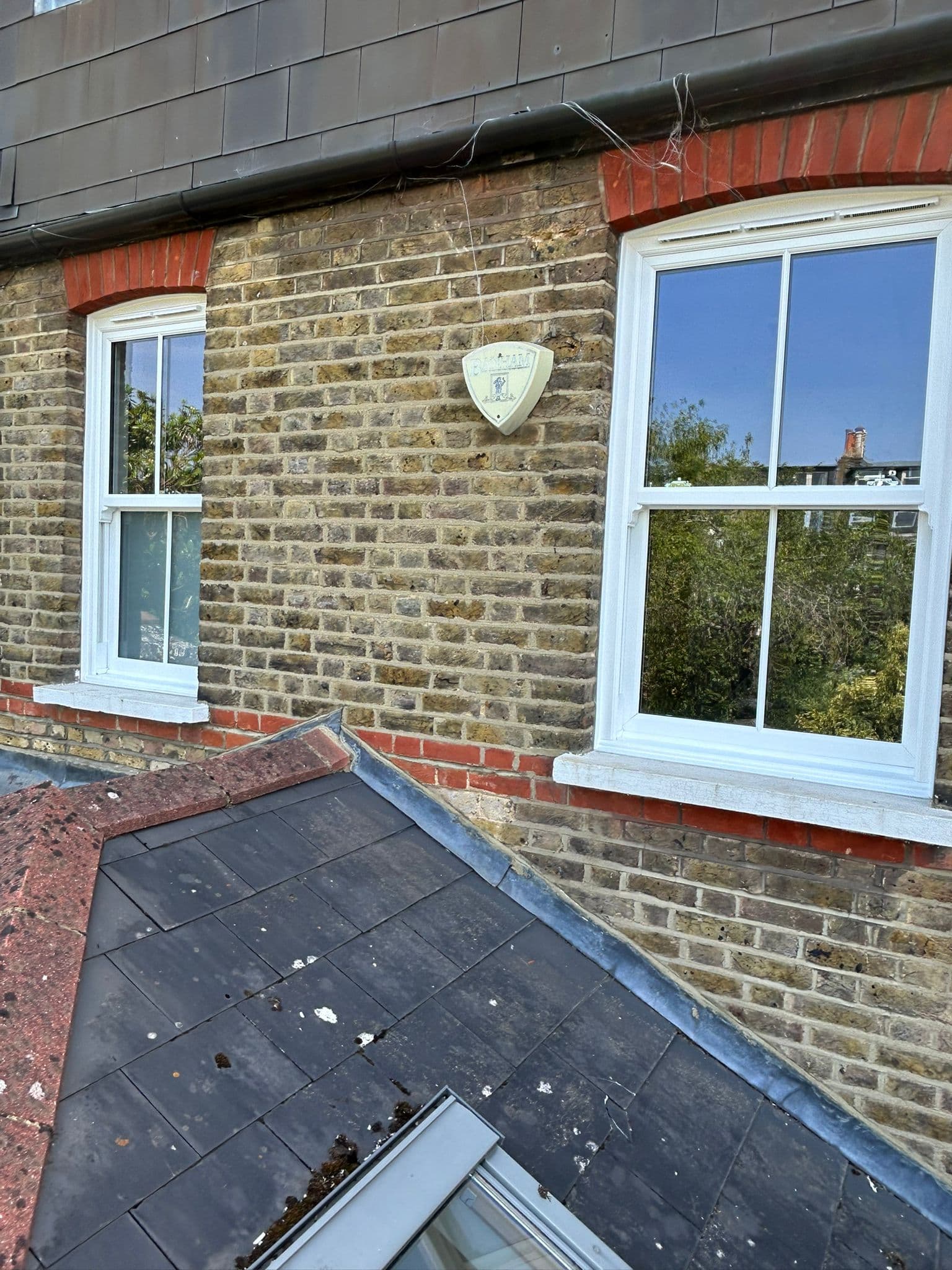 Two new white sash windows on Victorian brick exterior — London